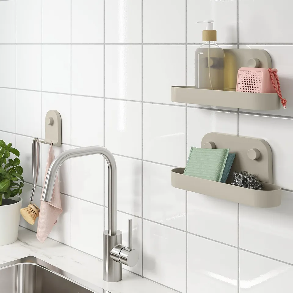 Beige wall organisers with suction cups hang on tiled wall beside kitchen sink, holding cleaning supplies and towels.