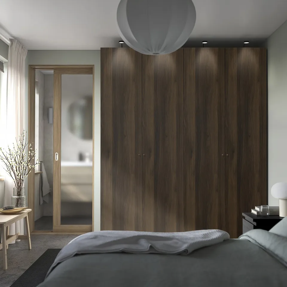 Bedroom with large wardrobe, lamp, side table, and mirror.