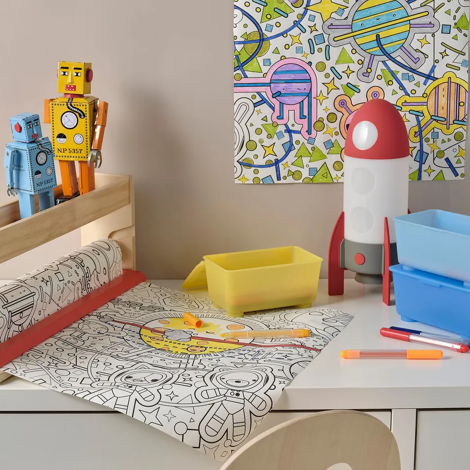 Childs space-themed desk with lamp, bins, markers, and paper, featuring a rocket-shaped lamp that changes colours.