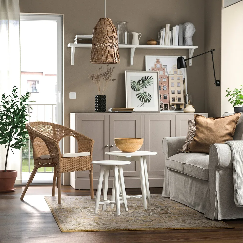 Cosy living room with wicker chair, grey sofa, JÄRNVÄG rug in pastels, side table, book cabinet, and large window.