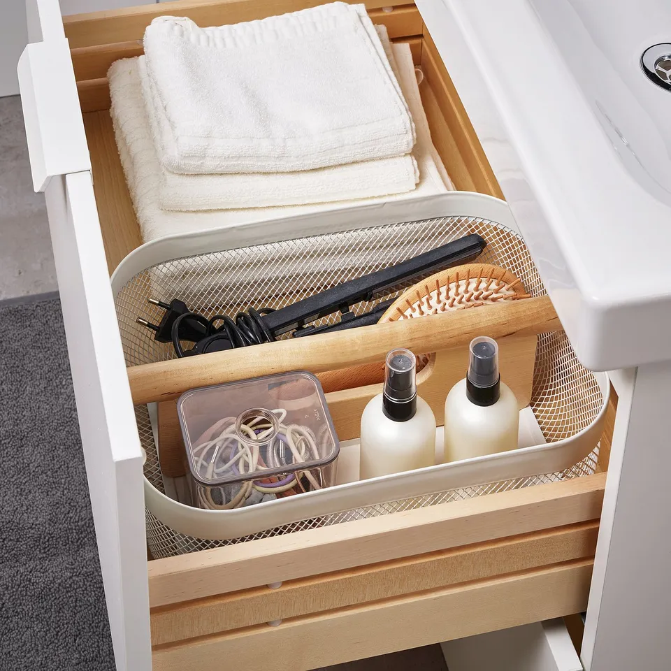 Organised bathroom drawer with RISATORP divider: towels, hairbrushes, bottles, and accessories neatly stored.