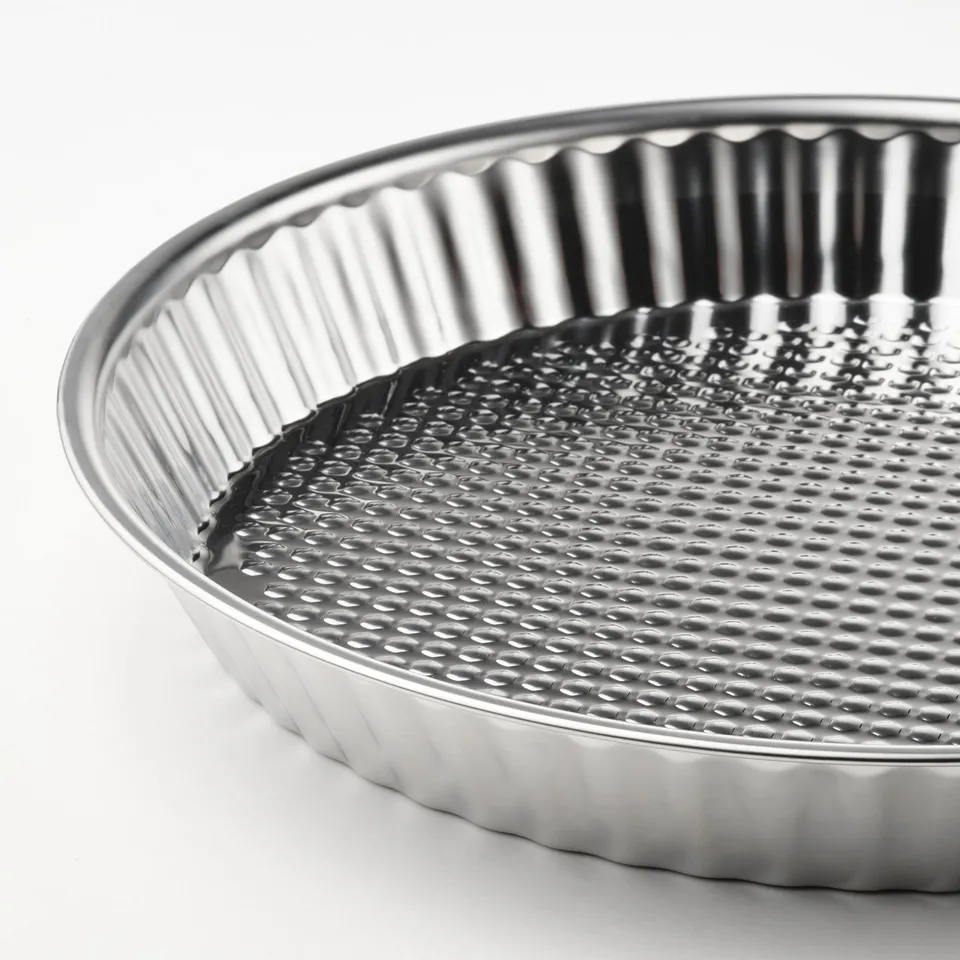 Metal pie dish with fluted edges and textured base, made of stainless steel.