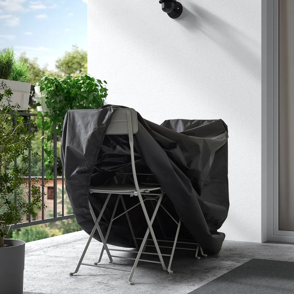 Black waterproof cover shielding outdoor furniture from weather on balcony.