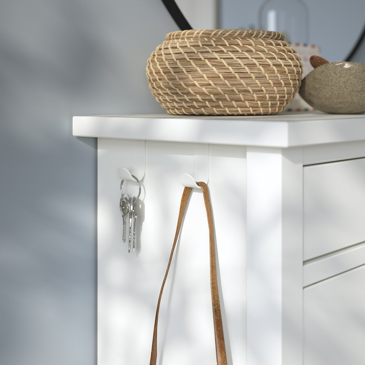 White shoe cabinet with woven basket and hanging keys.