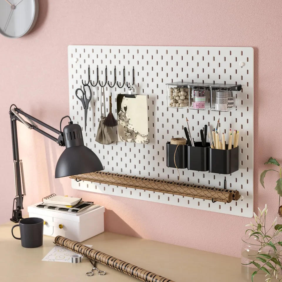 Organised office setup: pegboard with containers, scissors, and lamp.