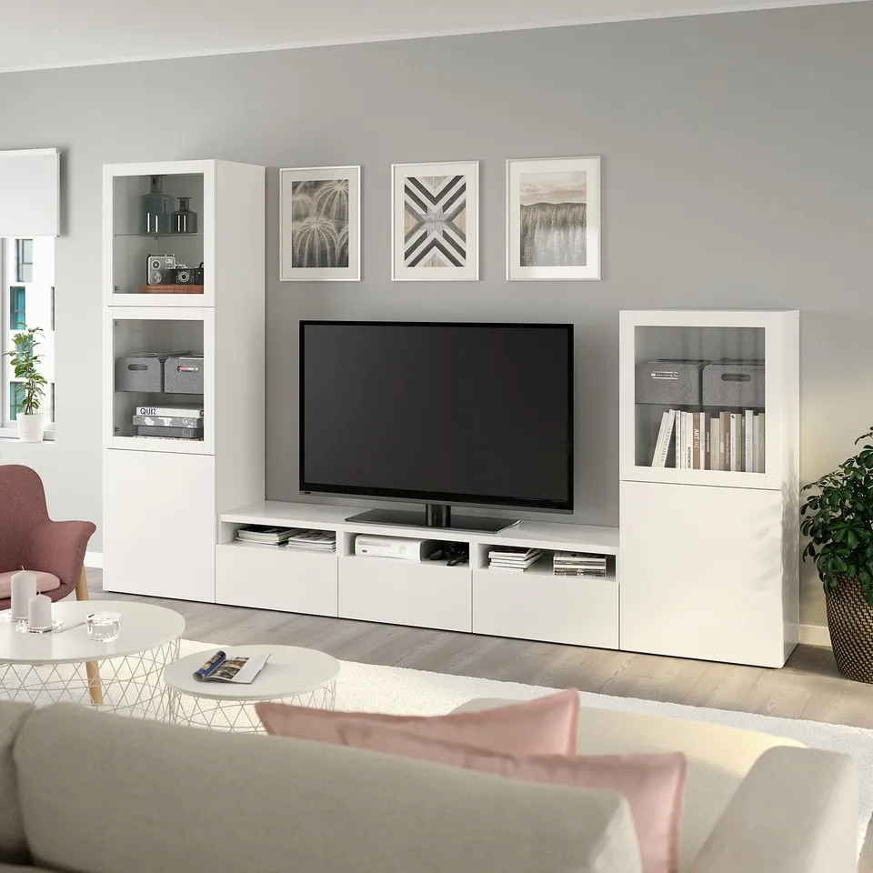 Contemporary living room with white BESTÅ tv storage, display cabinets, grey sofa, pink accents, and coffee table.