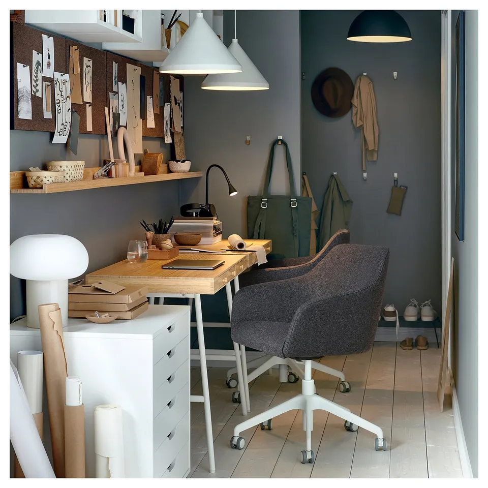 Modern home office with TOSSBERG grey swivel chair, wooden desk, pendant lights, and grey walls.