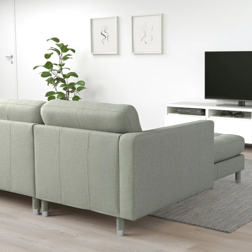 Modern minimalist living room with light green LANDSKRONA sofa, large flat-screen tv, sleek media centre, decorative plant, and wall art.