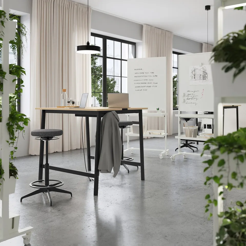 Modern office with high tables and stools, ideal for standing or sitting meetings; includes footrests and cable management for convenience.