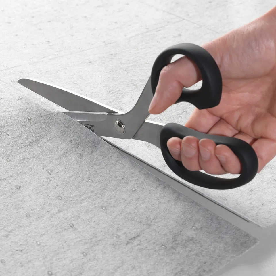 Cutting a grey felt mat with scissors for drawer fitting.