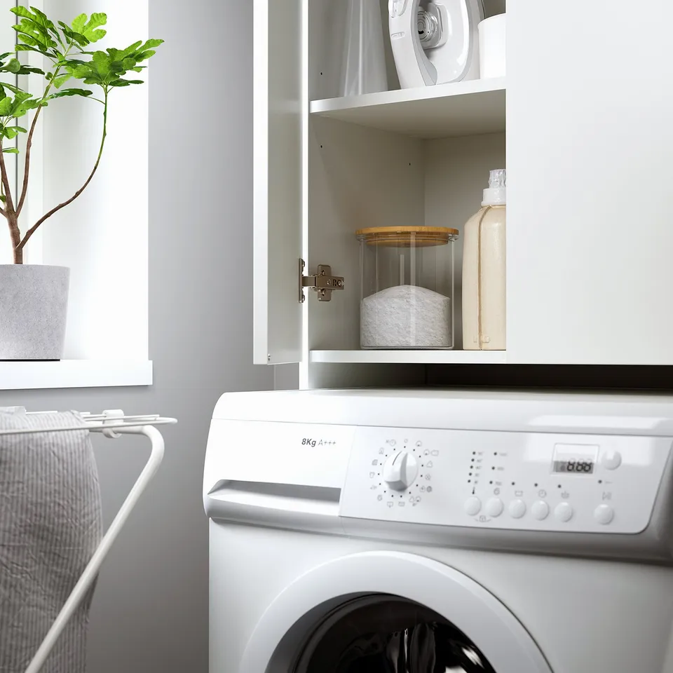 Laundry cabinet above washer, holding detergent and cleaning supplies, utilising space efficiently.