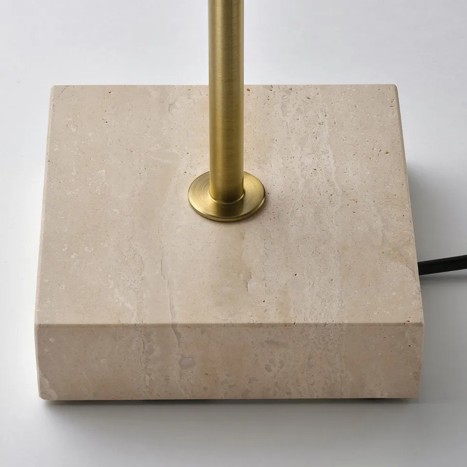 Square beige travertine base with a smooth brass-colored pole, showing high-quality craftsmanship and natural stone texture.