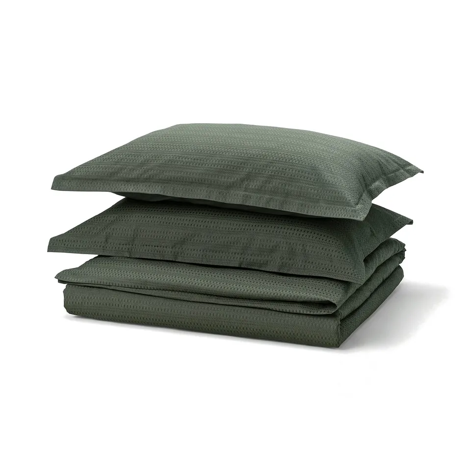 Dark green LUKTVICKER duvet set, featuring waffle weave cotton texture, neatly folded on a white surface.