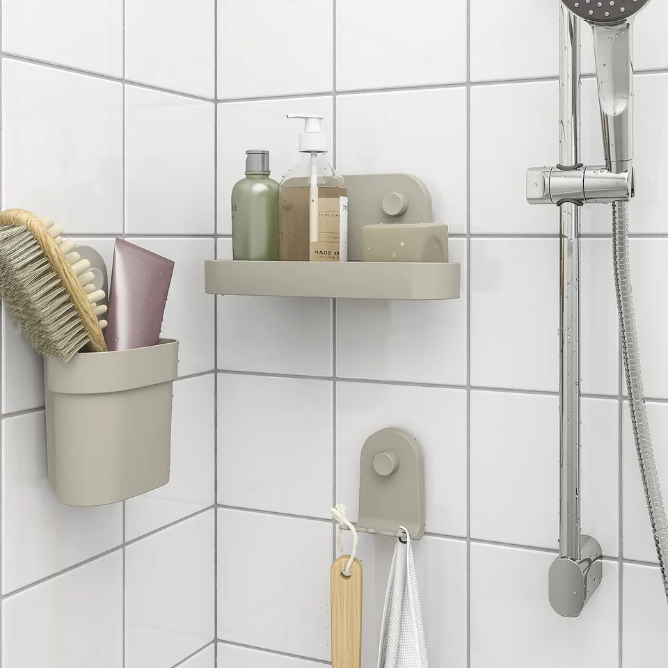 Bathroom wall organiser with suction cups, holding shower essentials, brush, and bottles.