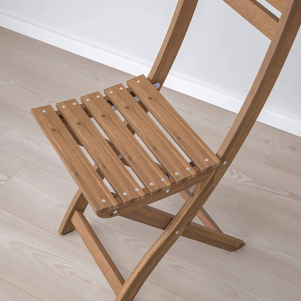 Wooden folding chair with slatted seat, stylish and durable, angled on light wooden floor.