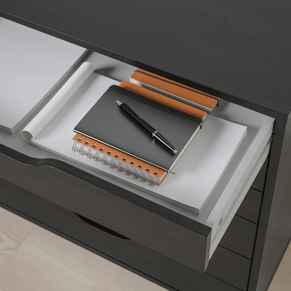 Desk drawer with notepad, pen, and paper roll, showing organised storage.