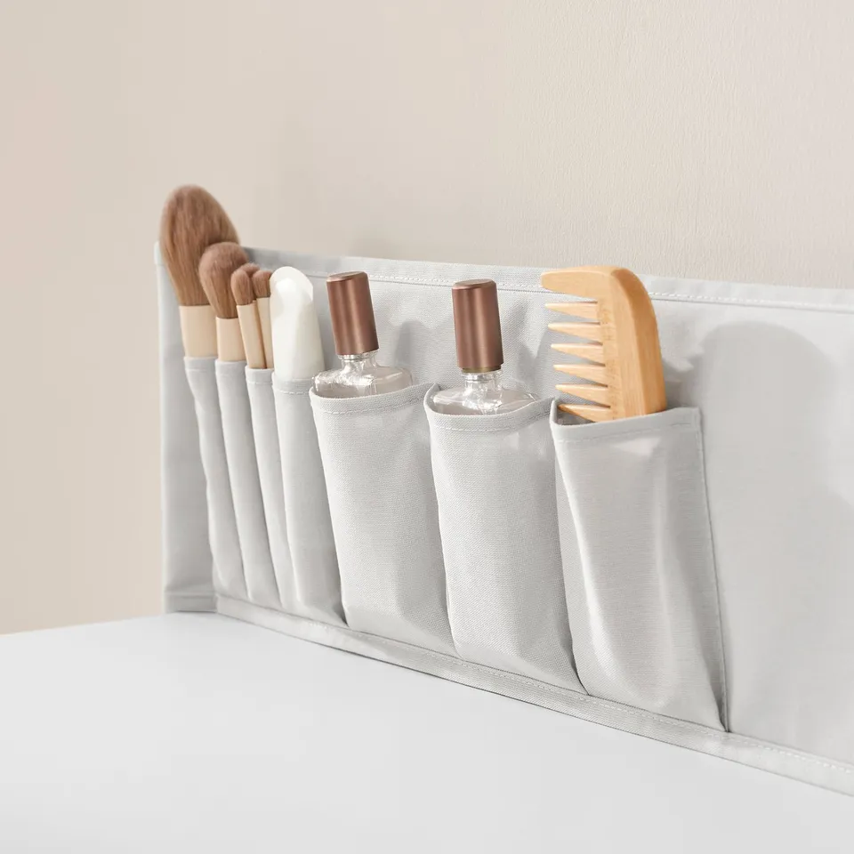 White organiser with fabric pockets holds makeup brushes and tools neatly; ideal for keeping items tidy and accessible.