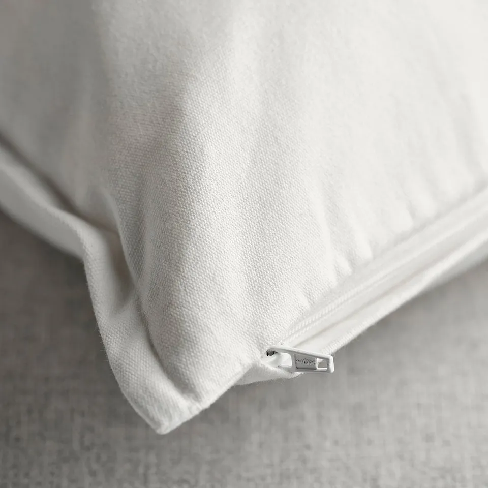 Close-up of a white cushion cover with a hidden zip, smooth fabric, clean finish, and embroidered design.