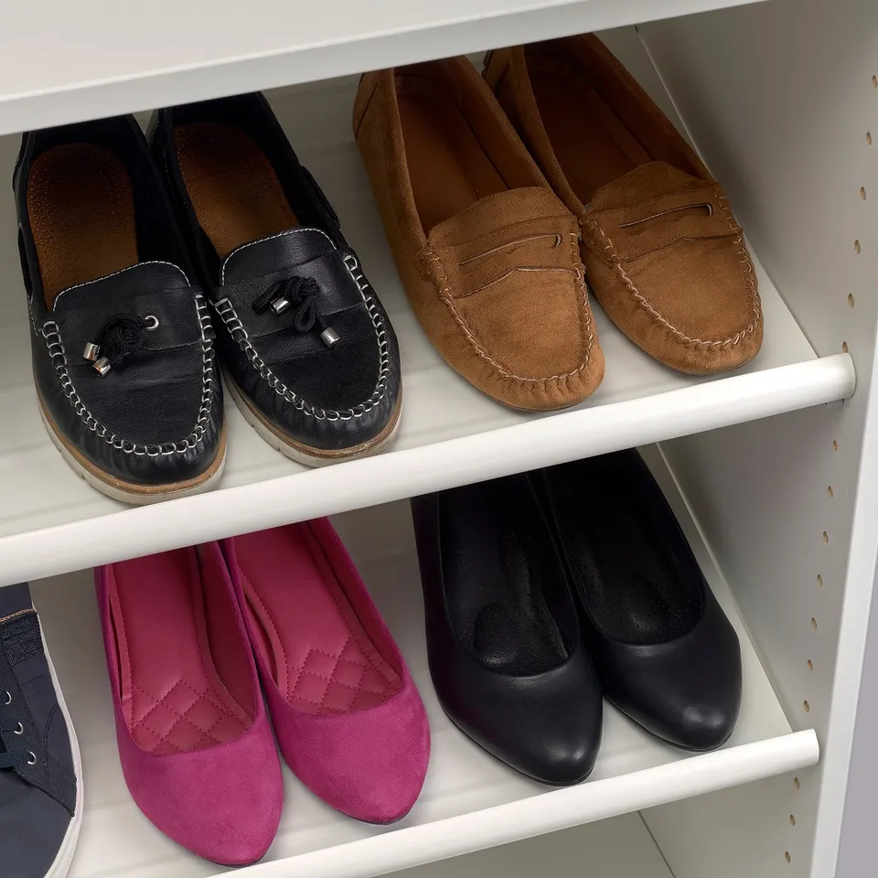 Shoe organiser with white shelves holding pairs of loafers; colours include black, brown, and pink.