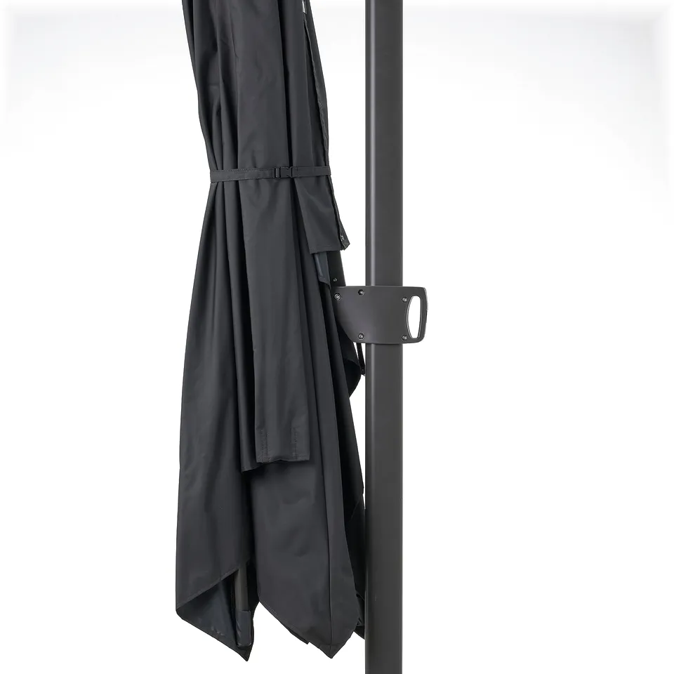 A black patio umbrella, tilted and secured with a buckle strap, attached to a metal pole, offering 50+ uv protection.