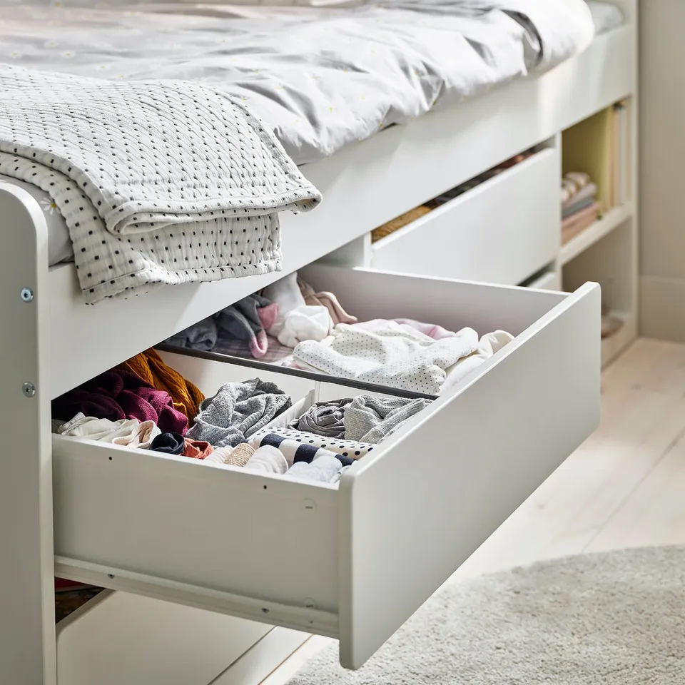 Under-bed drawer, part of SLÄKT series, showing organised storage with folded clothes. Easy access and space-saving design.
