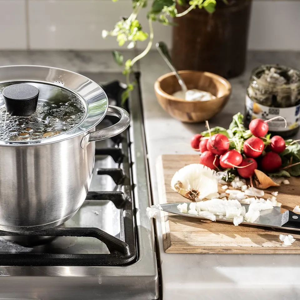 Glass lid, veggies, cutting board on stove.