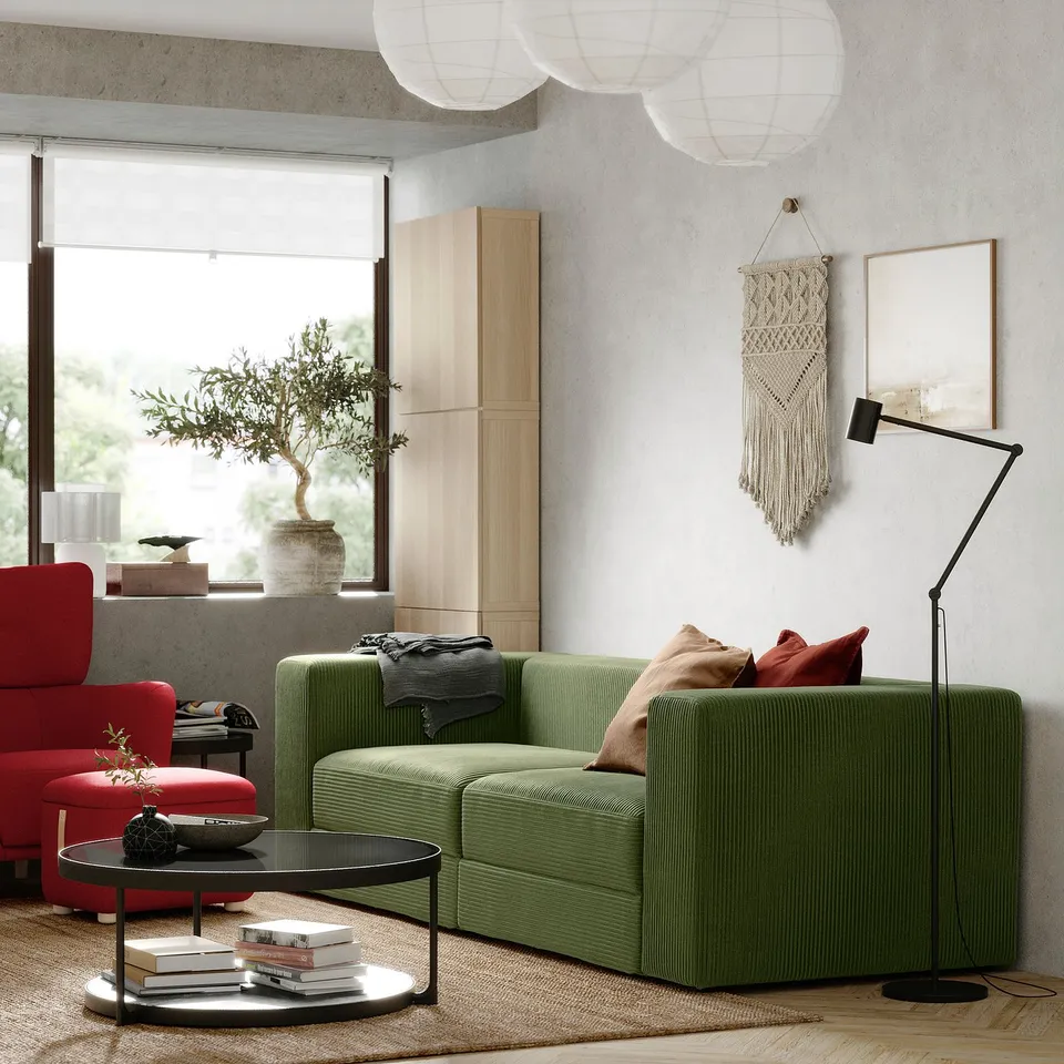 Modern living room: green l-shaped JÄTTEBO sofa, red armchair, coffee table, plant, large window, wall art, floor lamp.