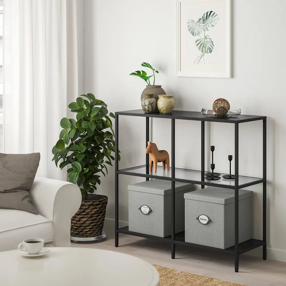 Modern living room with KVARNVIK boxes on metal shelf. Decor: plants, vases, wooden horse. Boxes fit under shelf.