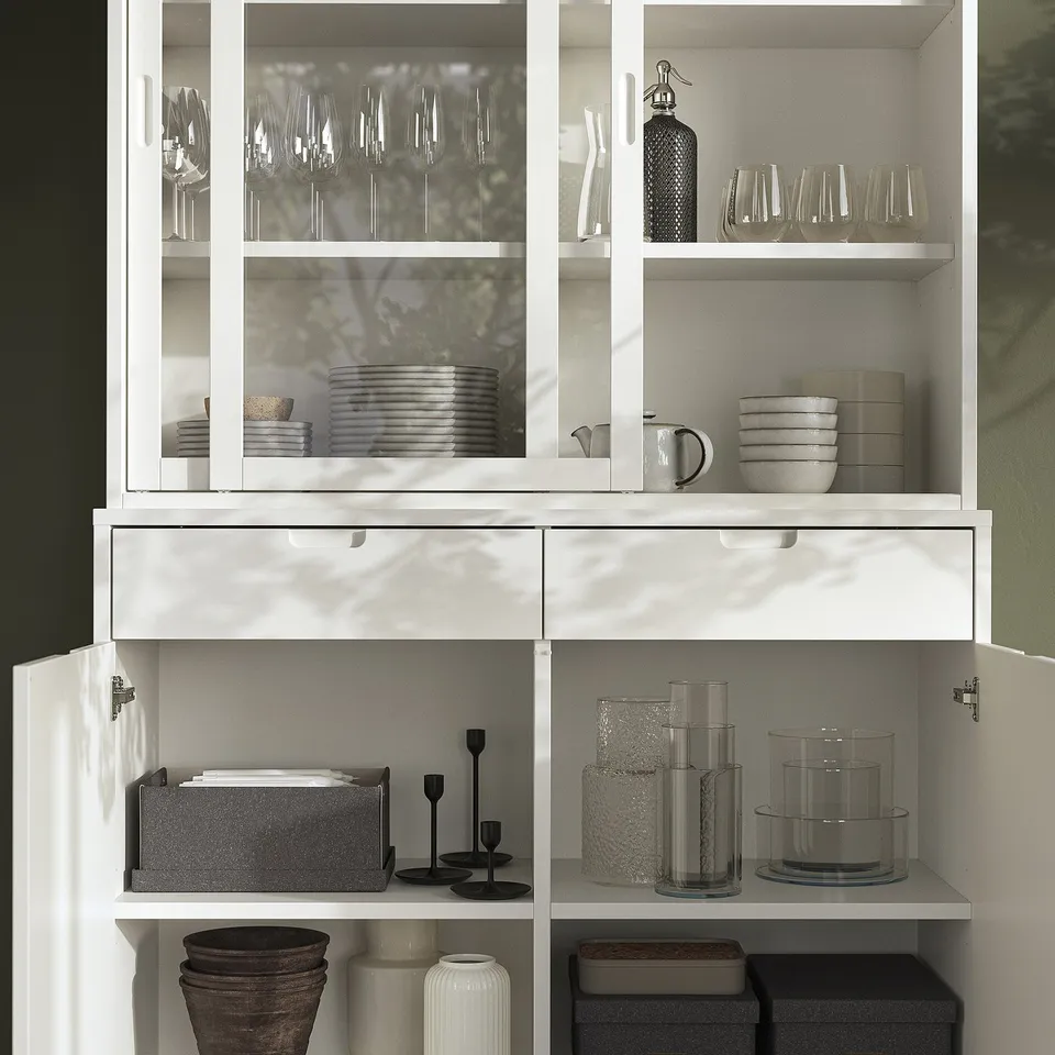 Modern off-white dining cabinet with glass doors, storing plates, glasses, and vases neatly. Drawers and adjustable shelves.