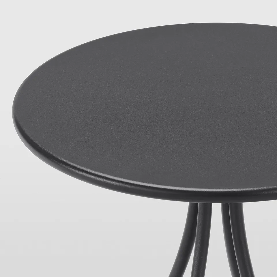 Round black side table on three legs. Smooth, durable surface with sturdy support. Modern minimalist design.