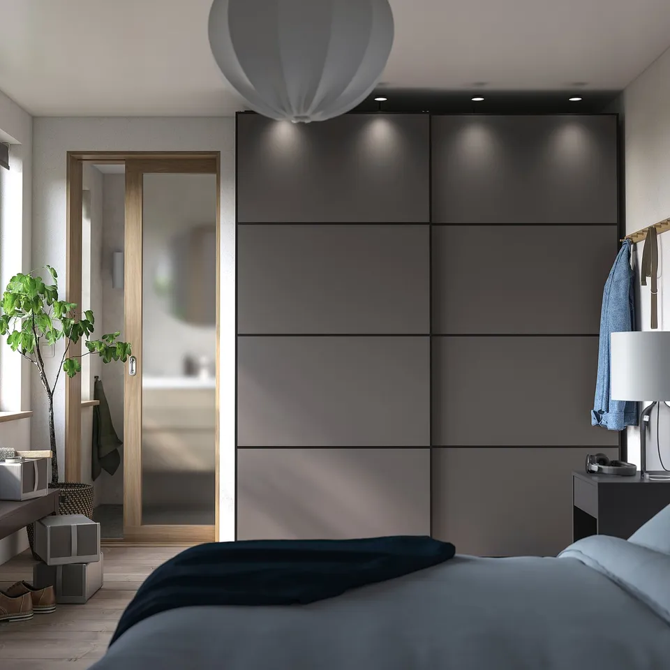 Modern bedroom with grey wardrobe, hanging lamp, bed, plant, mirror, and hanger.