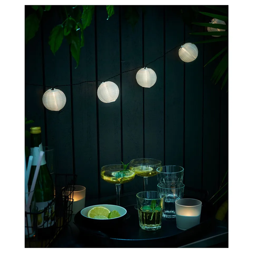Solar-powered lanterns illuminate an outdoor table with cocktails and candles.