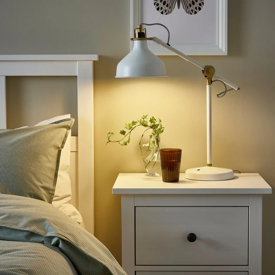 Stylish bedroom with RANARP lamp, greenery, and minimalist decor.