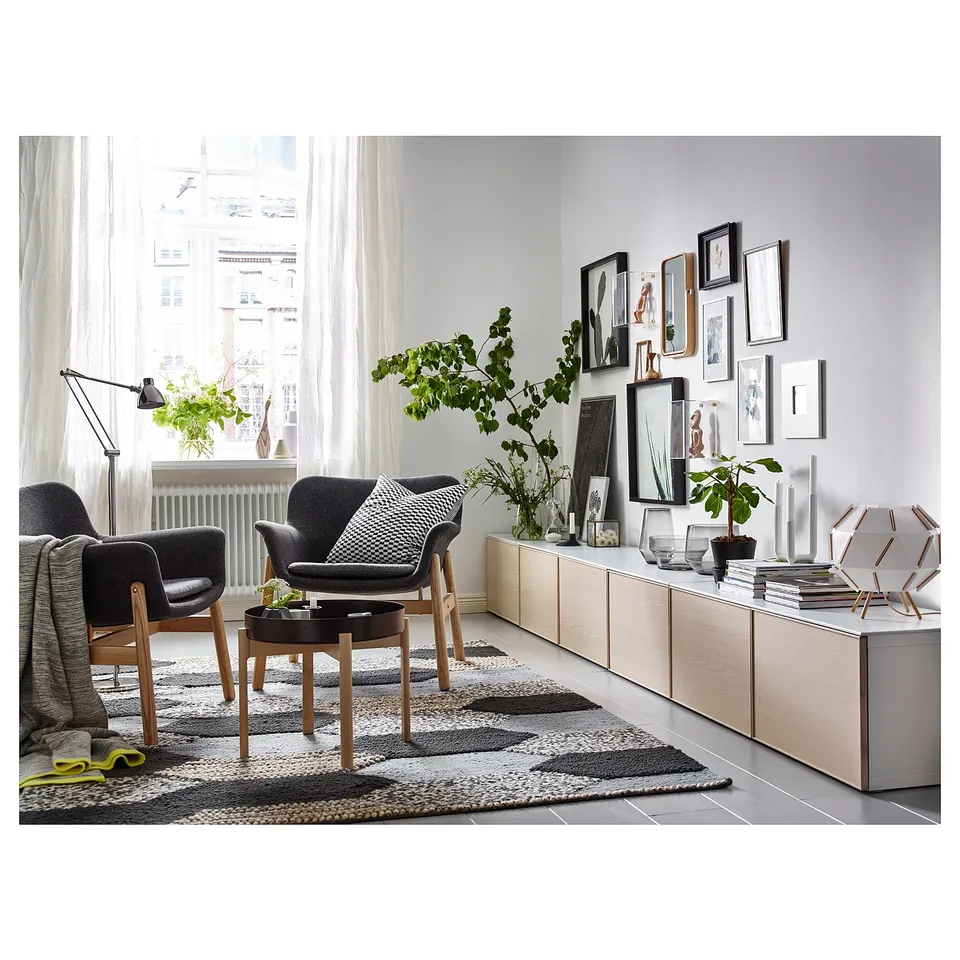 Modern living room with VEDBO dark grey armchairs, wooden coffee table, and light-colored storage unit with plants and framed pictures.