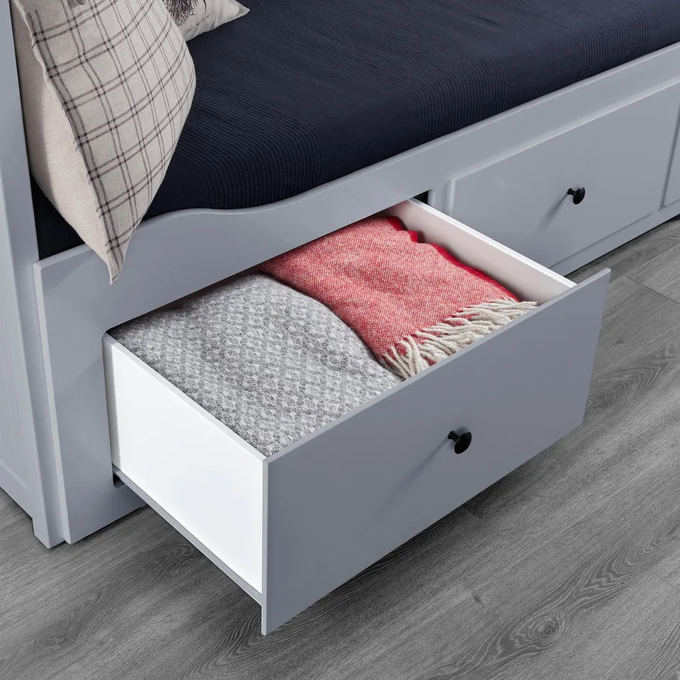 Open drawer of white daybed showing folded blankets.