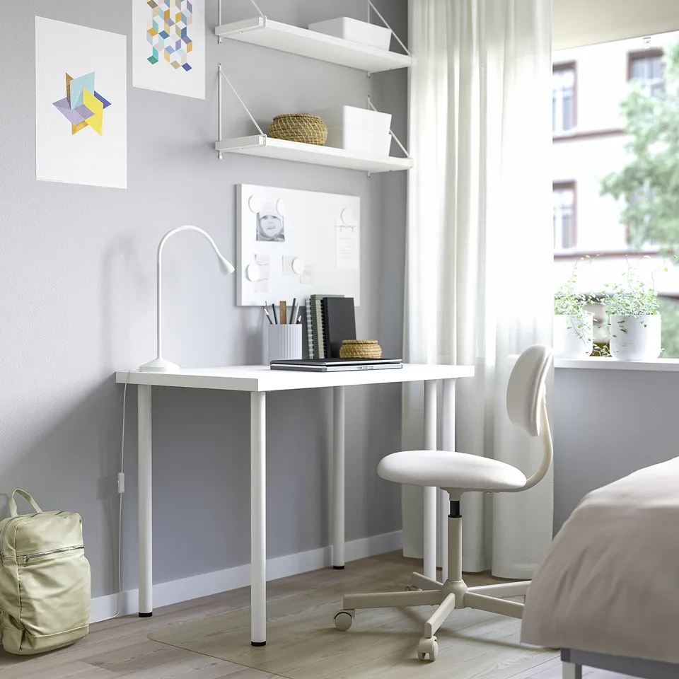 Minimalist home office setup: white LINNMON desk & chair by window, with shelves & art.