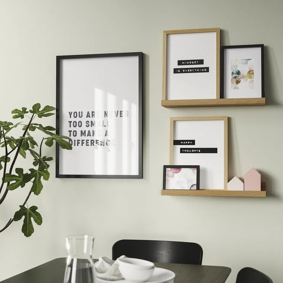A motivational poster wall with a you are never too small quote. Below, a dining table with a pitcher and cups, and a potted plant.
