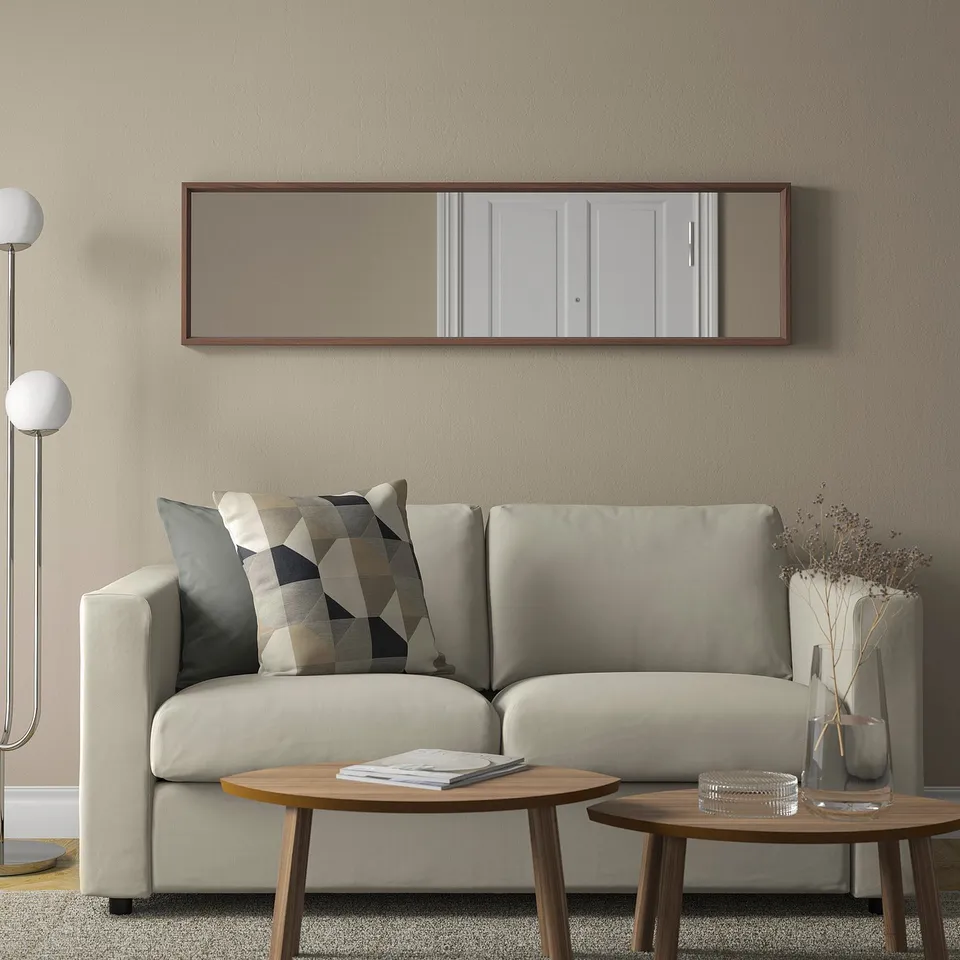 Living room with beige mirror over grey sofa, cushions, and side tables with decor.