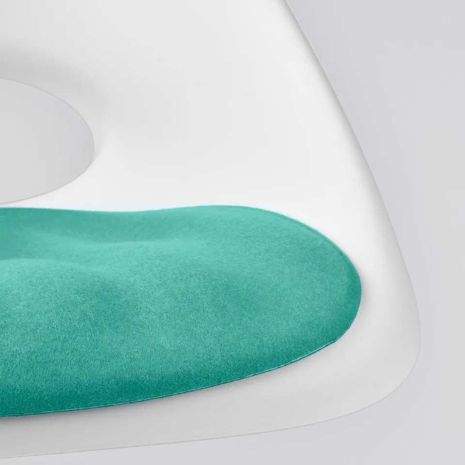 Green cushioned seat pad on white chair. Soft, recycled material.