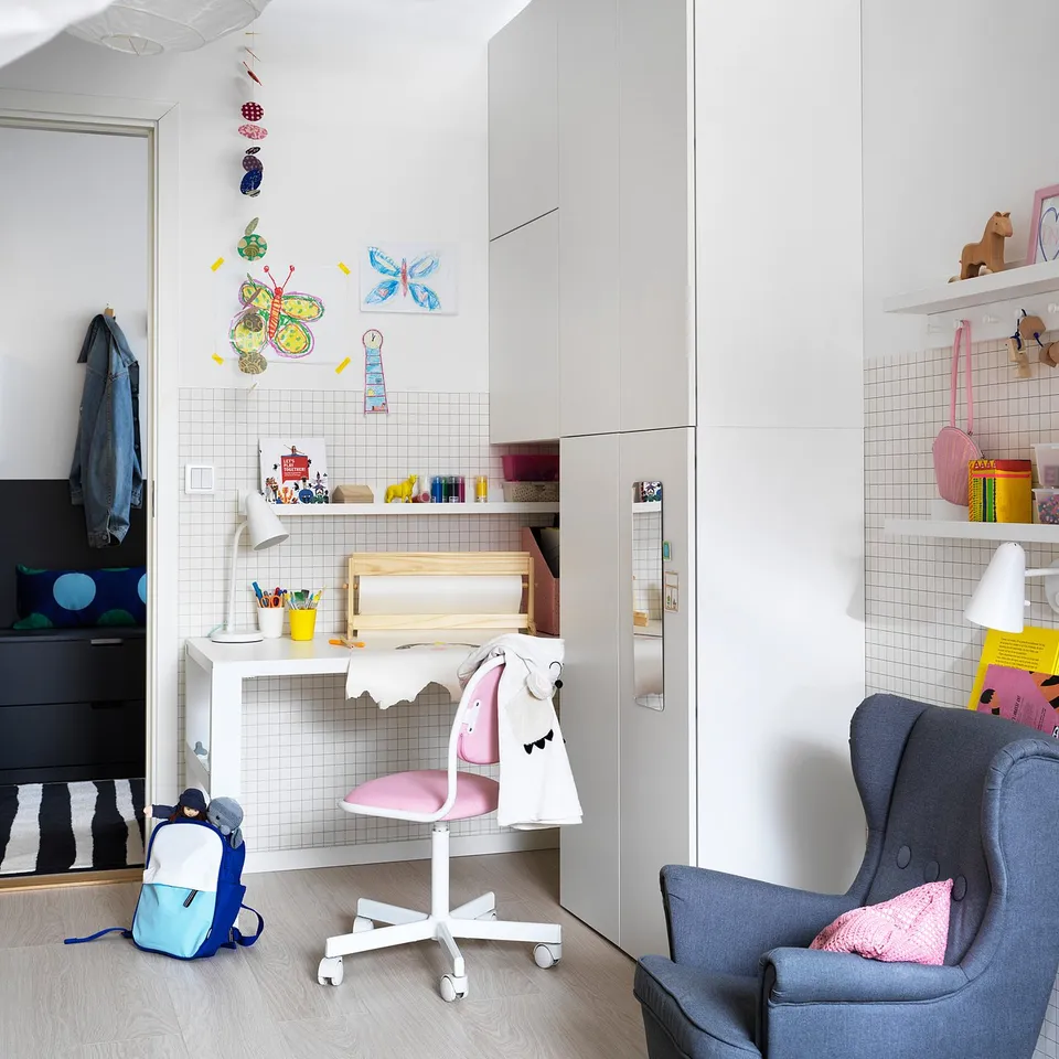 Childs room with adjustable desk chair, armchair, dresser, decorations, backpack.