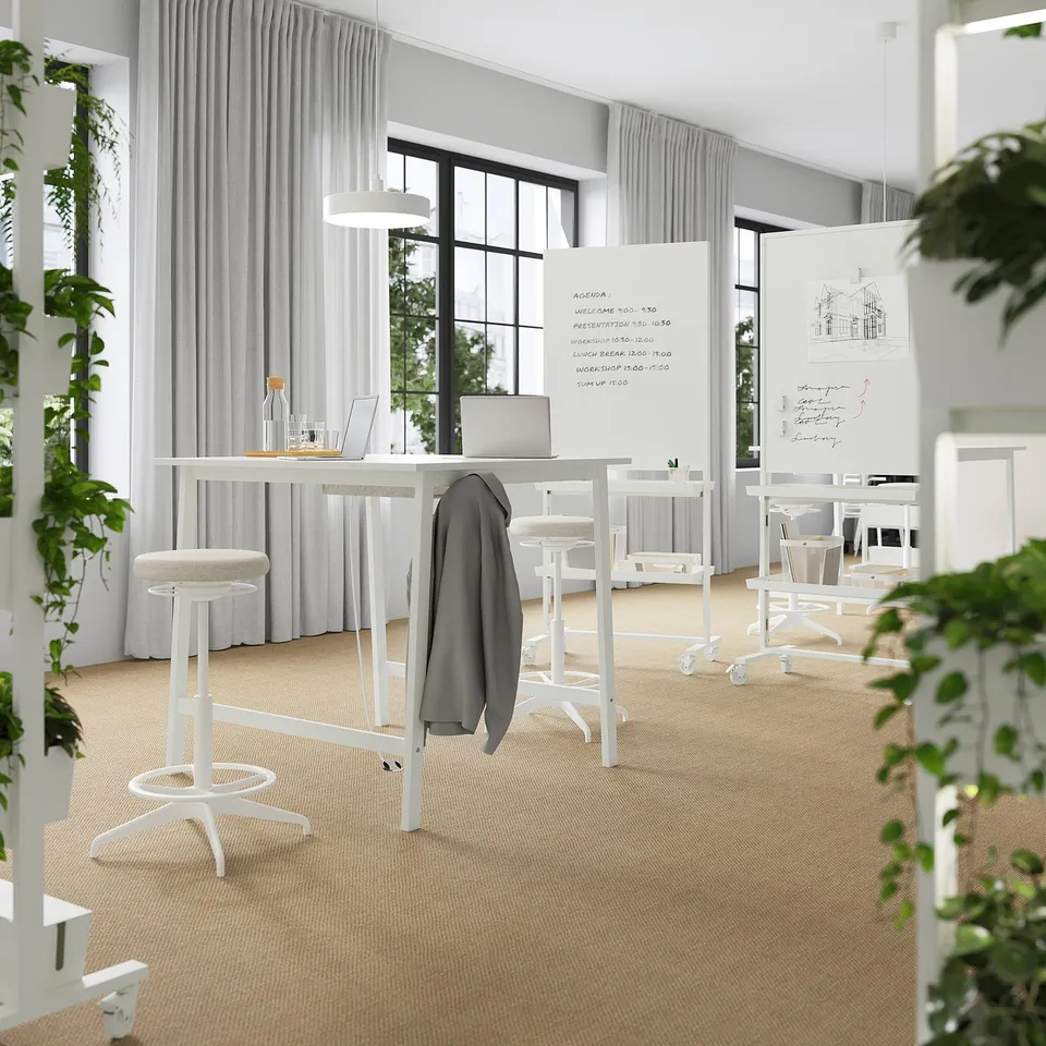 Modern conference room with high tables and laptops, natural light.