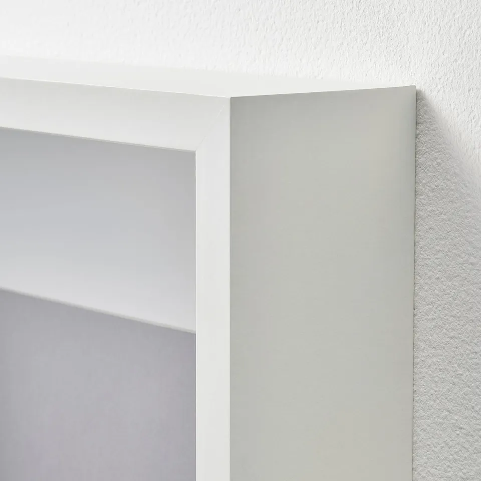 A white picture frame with a sleek, smooth finish hangs on a plain wall, showing its sturdy construction and minimalist design.
