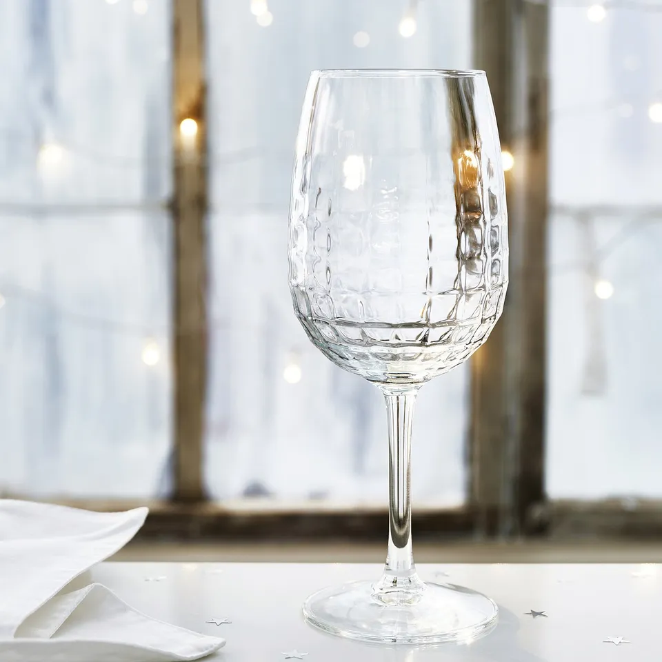 Faceted wine glass on table, elegant design, clear glass.