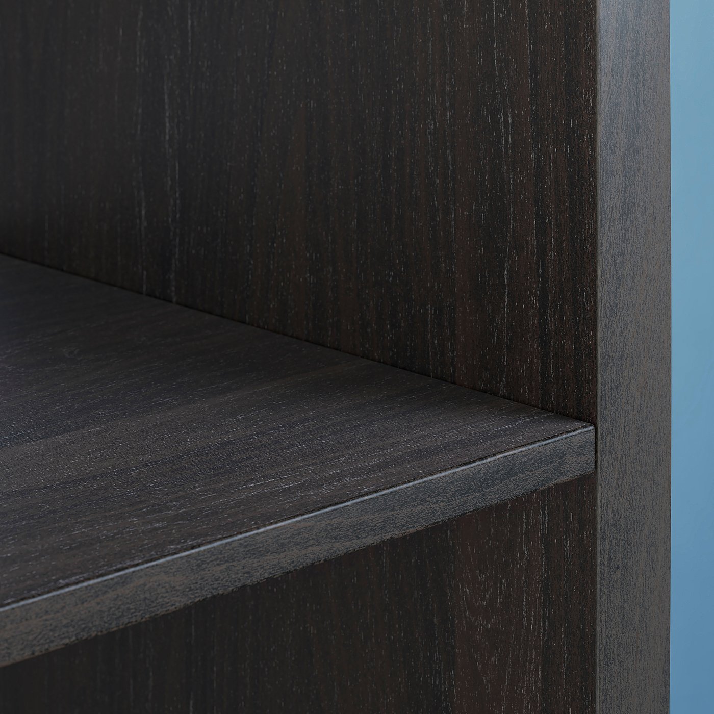 Black KALLAX shelf unit made of particleboard with horizontal shelves against blue backdrop.