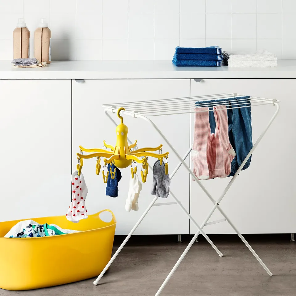 Unique dryer with octopus design holds socks & baby clothes, next to laundry basket & cabinets.