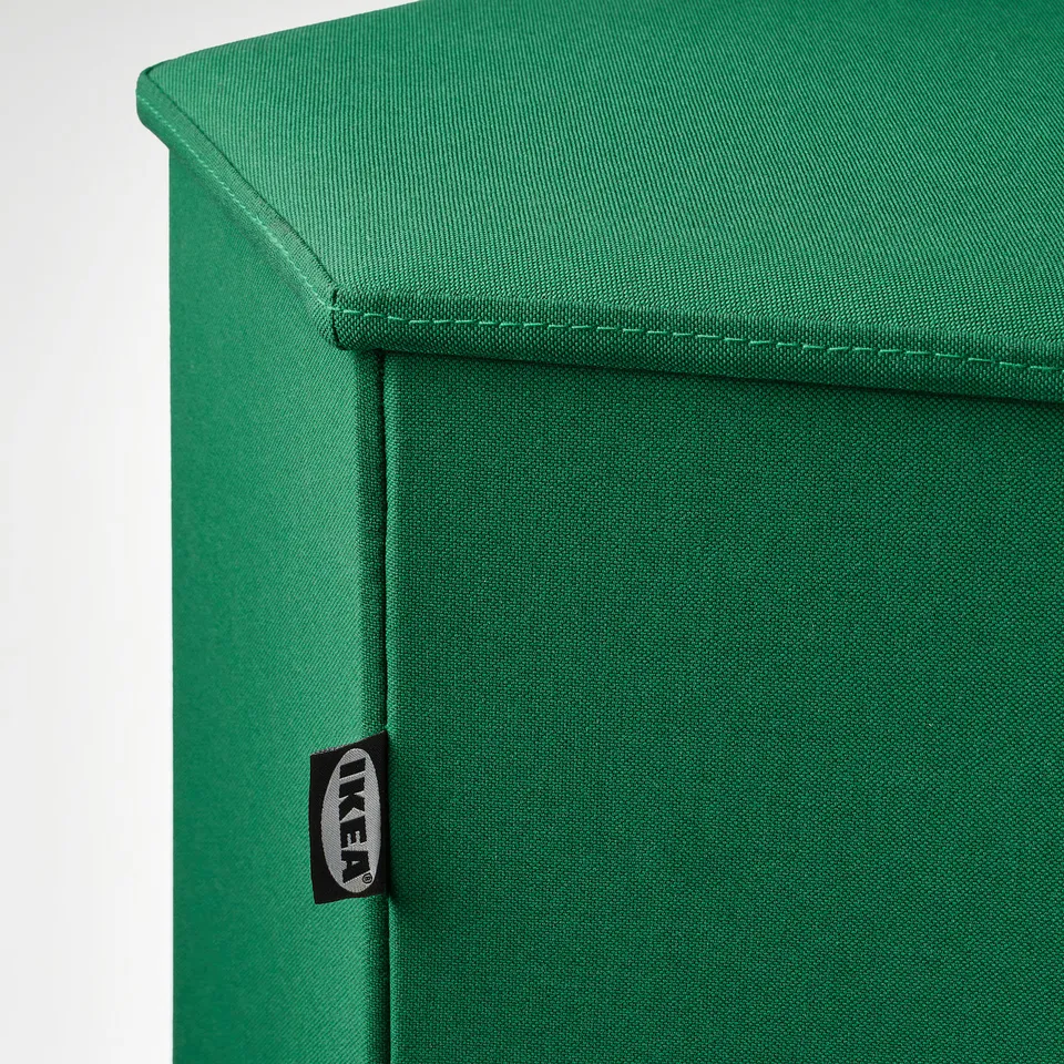 Green upholstered furniture corner, showing stitching details and IKEA tag.