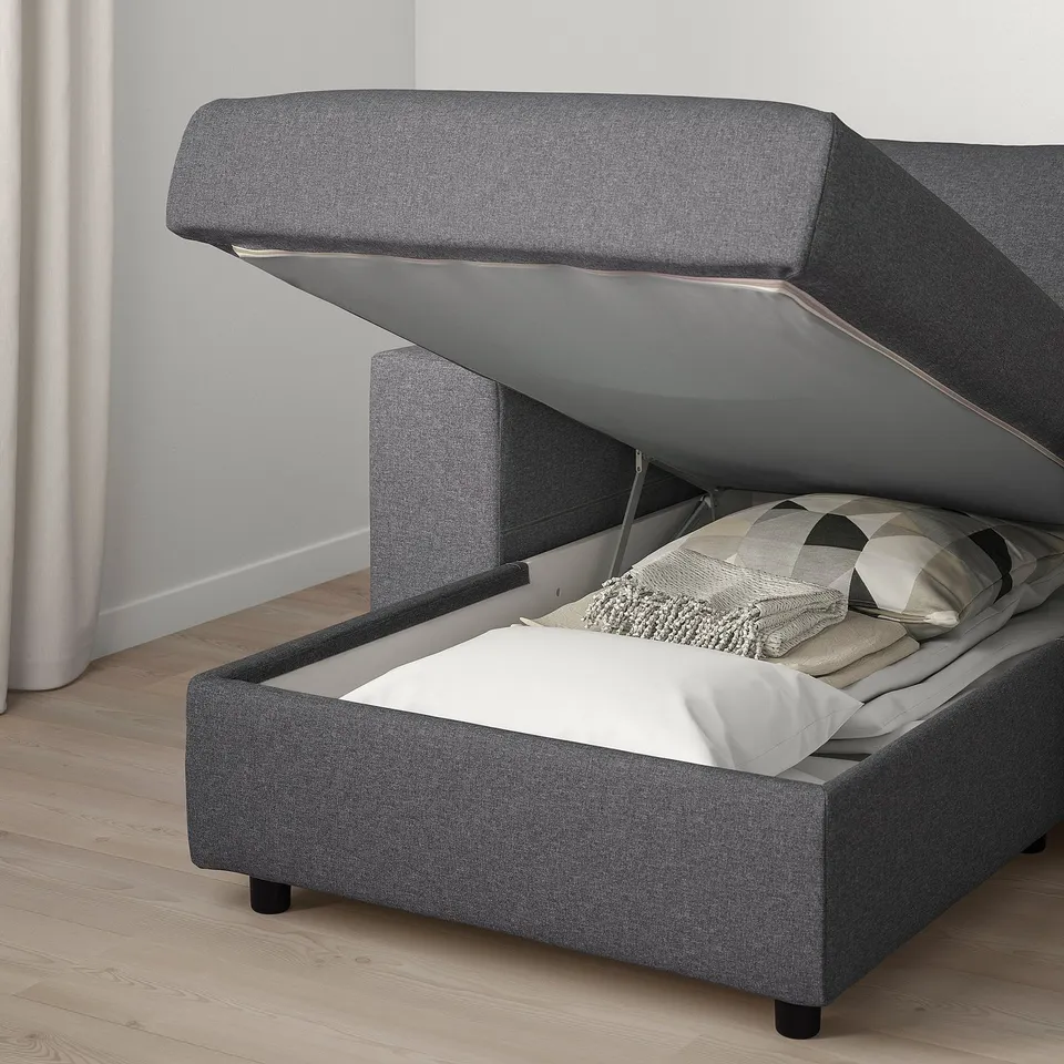 Grey sofa-bed open, revealing thick mattress and storage space.