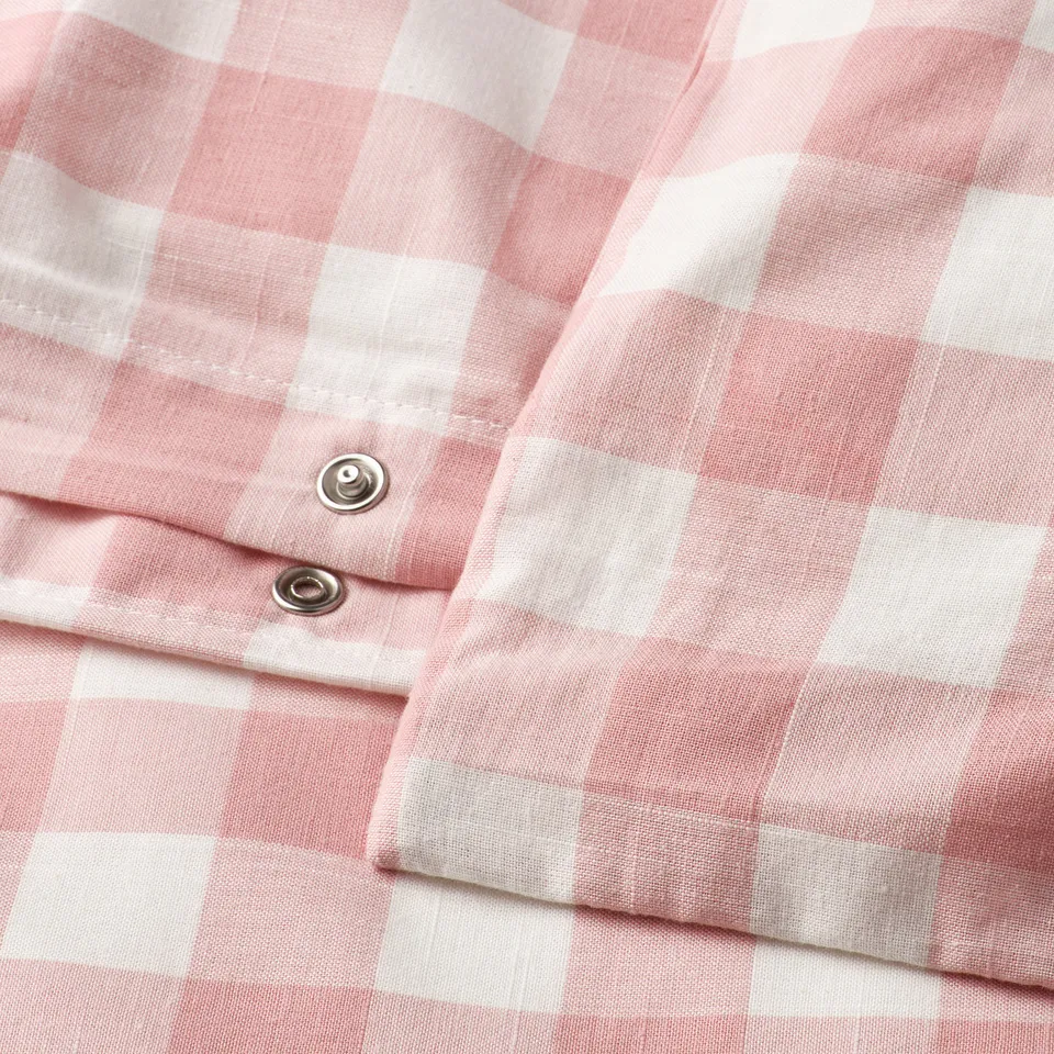 Close-up of a pink and white chequered duvet cover with metal press-stud closure at the bottom.