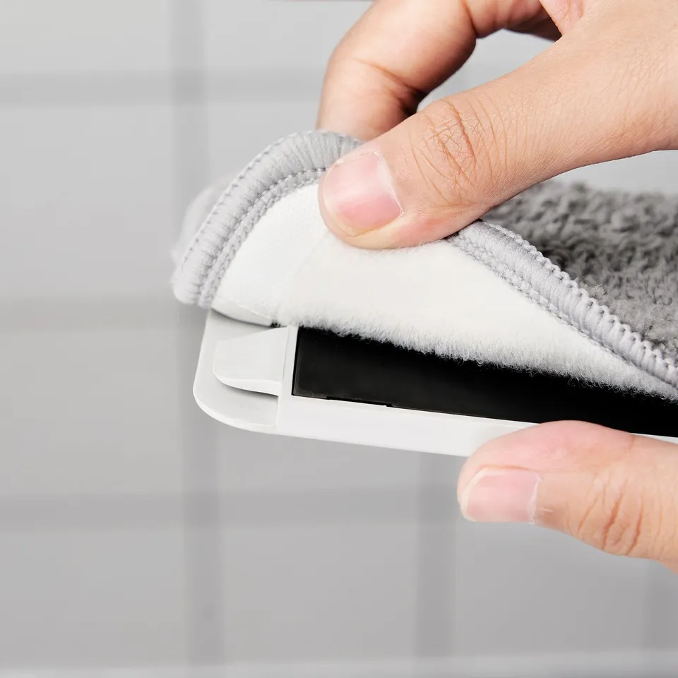 Person holding a microfiber cloth mop refill, showing its absorbent and quick-drying.
