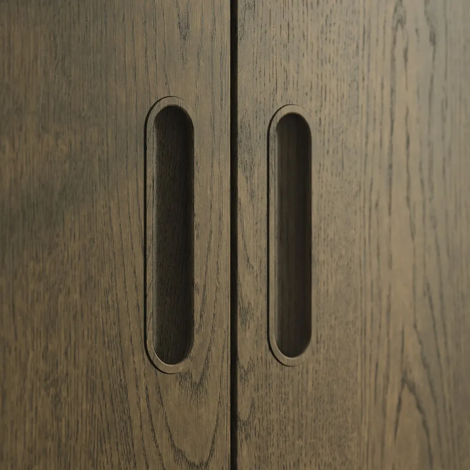 Wooden cabinet with two dark handles, dark handles are oval and elongated.